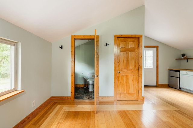spare room featuring vaulted ceiling, baseboards, and light wood finished floors