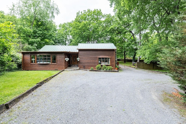 rustic home featuring driveway and metal roof