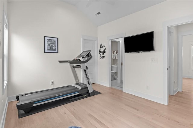 exercise area featuring light wood-style flooring, baseboards, and lofted ceiling