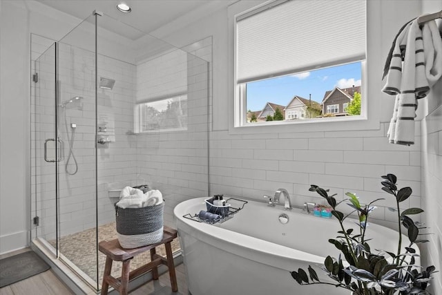 bathroom featuring a shower stall, a freestanding tub, recessed lighting, and tile walls