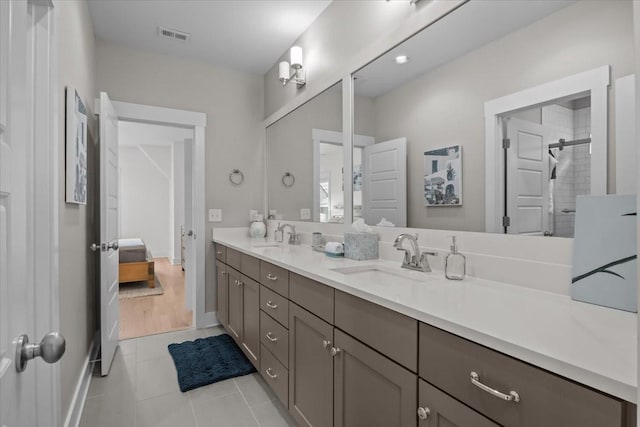 ensuite bathroom with tile patterned flooring, a shower stall, and double vanity