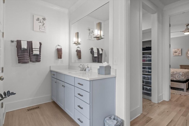 ensuite bathroom featuring wood finished floors, vanity, and baseboards