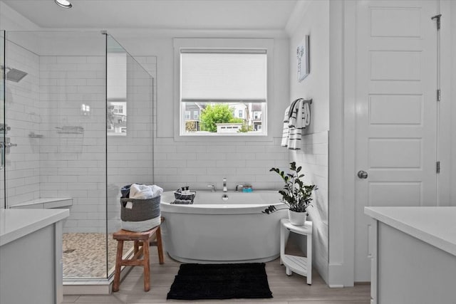 bathroom with a stall shower, a soaking tub, tile walls, and wood finished floors