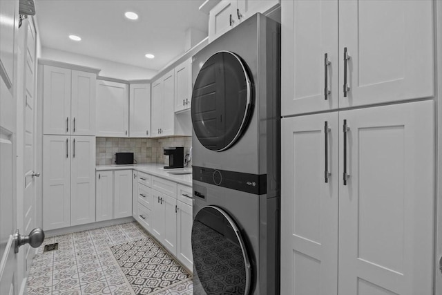 laundry area featuring stacked washing machine and dryer, cabinet space, and recessed lighting