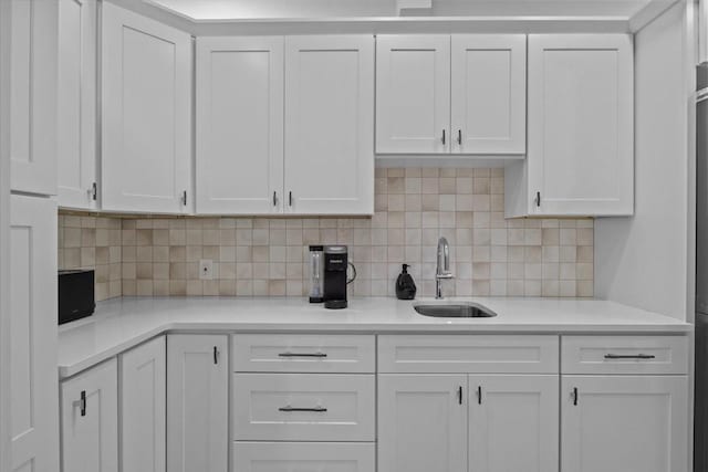 kitchen featuring a sink, light countertops, white cabinetry, and tasteful backsplash