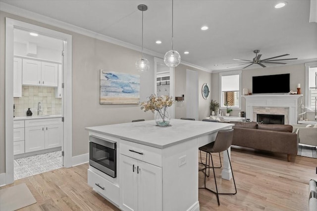 kitchen with stainless steel microwave, a kitchen bar, a center island, a sink, and recessed lighting