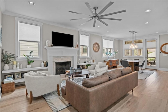 living area featuring crown molding, a high end fireplace, recessed lighting, light wood-type flooring, and ceiling fan