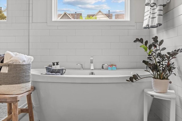 bathroom with tile walls, a freestanding bath, and tasteful backsplash