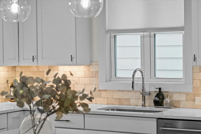 kitchen featuring stainless steel dishwasher, a sink, backsplash, and light countertops