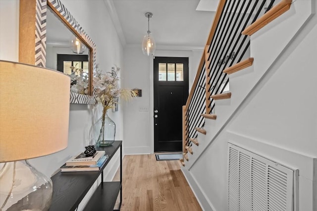 entrance foyer featuring wood finished floors, stairway, ornamental molding, and baseboards