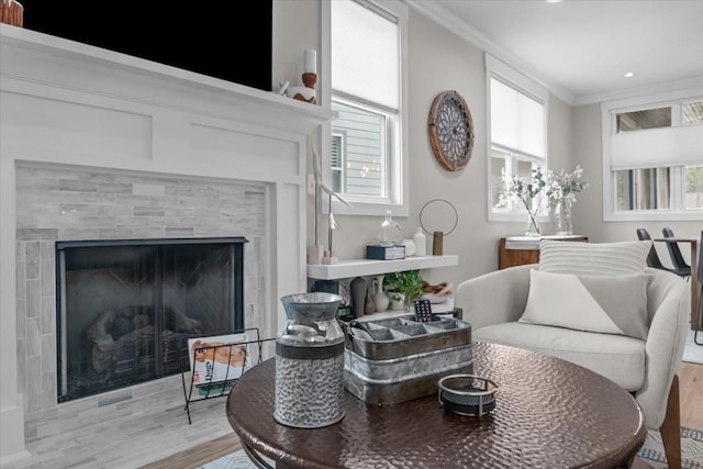 sitting room featuring crown molding, light wood finished floors, and a tile fireplace