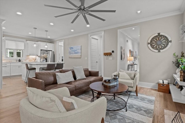 living room featuring ceiling fan, light wood-style floors, recessed lighting, ornamental molding, and baseboards