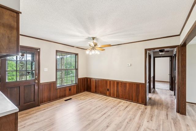 5245 Galen Rd, Lafayette, TN 37083 - empty room featuring a ceiling fan, light wood-style flooring, a textured ceiling, wainscoting, and ornamental molding
