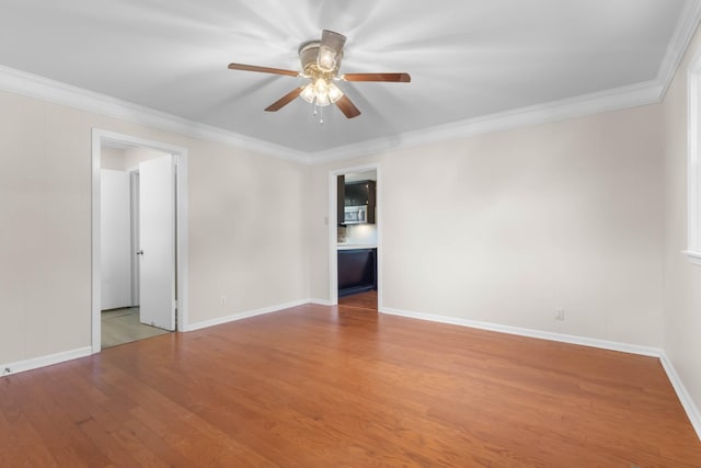 empty room with ceiling fan, wood finished floors, ornamental molding, and baseboards