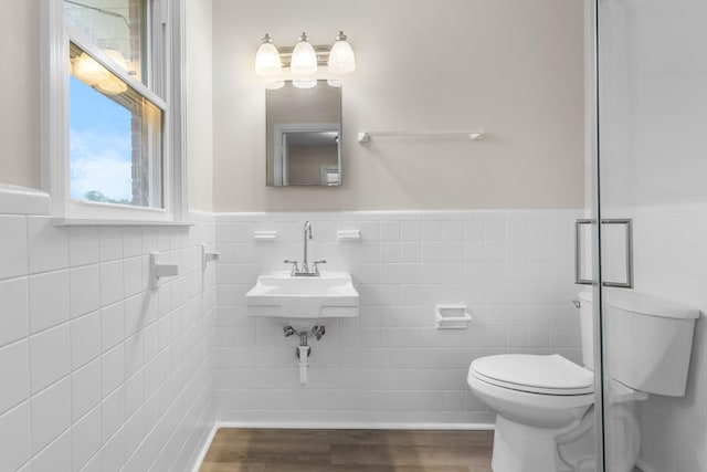 bathroom featuring toilet, tile walls, wainscoting, a sink, and wood finished floors