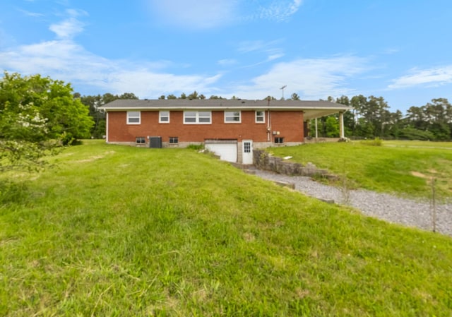 rear view of house with an attached garage, a yard, and driveway
