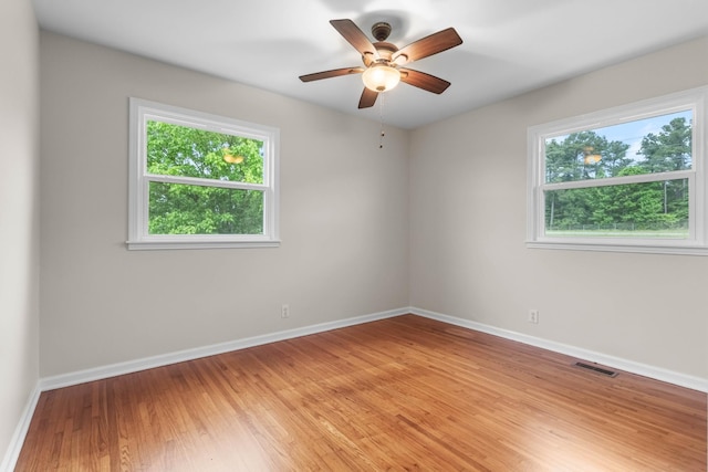 spare room featuring light wood-type flooring, baseboards, and a ceiling fan