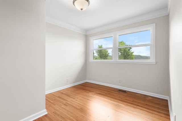 empty room featuring crown molding, baseboards, and light wood-style floors