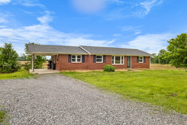 single story home with gravel driveway, brick siding, a front lawn, and an attached carport