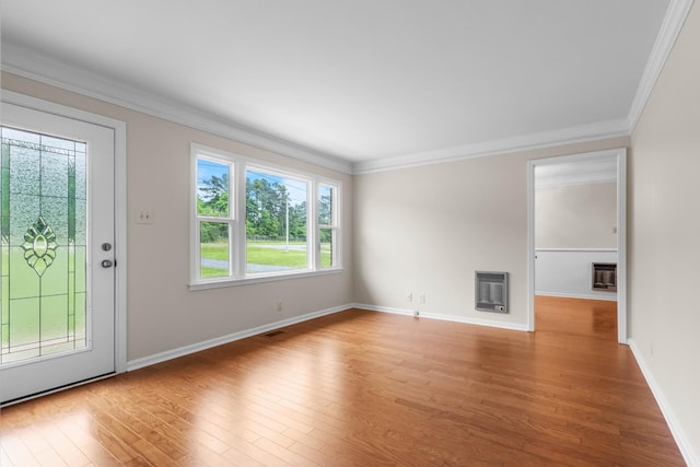 unfurnished living room featuring heating unit, wood finished floors, crown molding, baseboards, and a fireplace