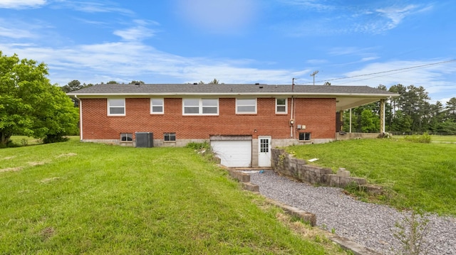 back of property with a garage, driveway, a yard, and brick siding