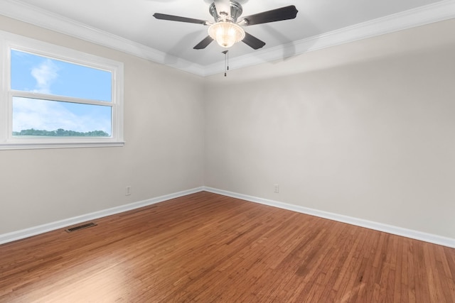 spare room with crown molding, wood finished floors, baseboards, and ceiling fan