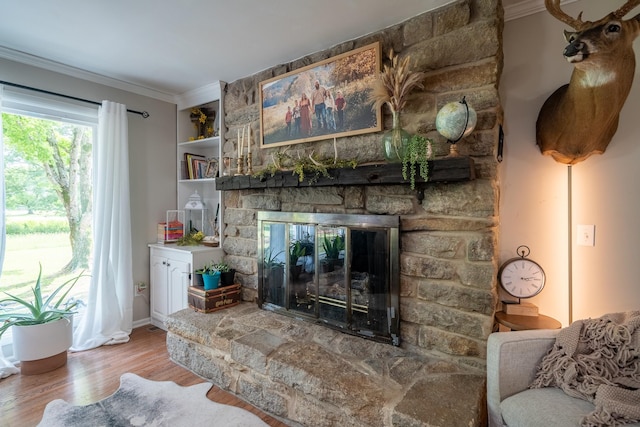living area featuring a fireplace, wood finished floors, crown molding, and baseboards