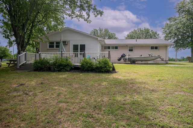 back of house with a wooden deck, a lawn, and brick siding