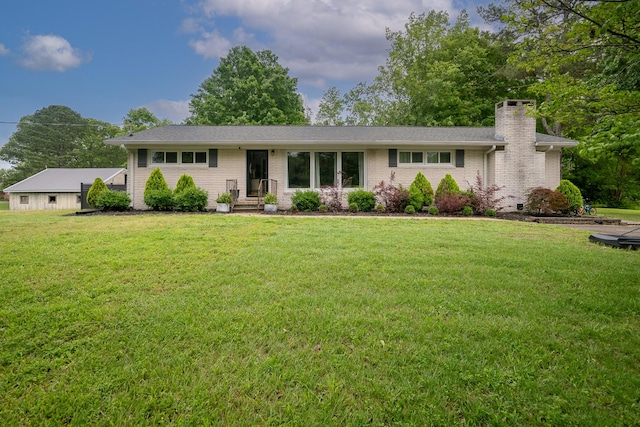 view of front of property with a chimney, a front yard, and brick siding