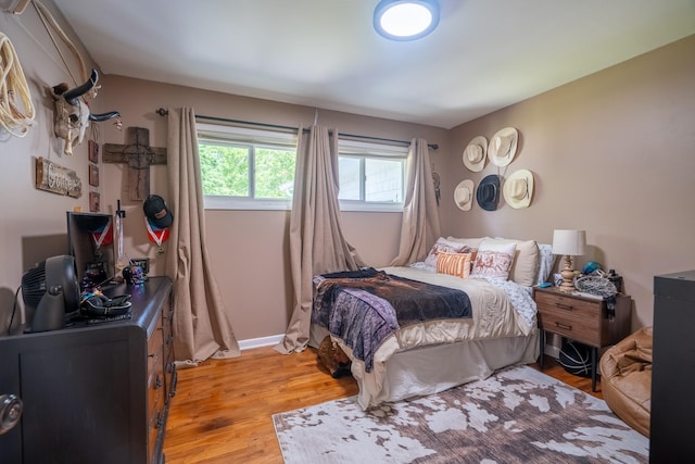 bedroom with light wood finished floors, an office area, and baseboards