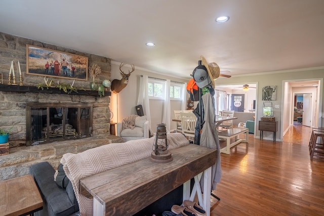 living area featuring crown molding, wood finished floors, a fireplace, a ceiling fan, and recessed lighting