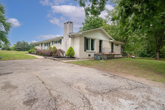 view of front of property with a chimney, brick siding, a front yard, and a wooden deck