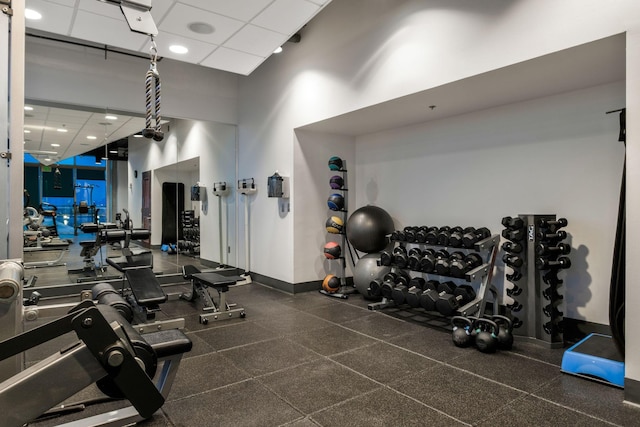 workout area with baseboards and a towering ceiling