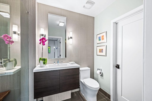 bathroom featuring tile walls, toilet, vanity, and tile patterned flooring