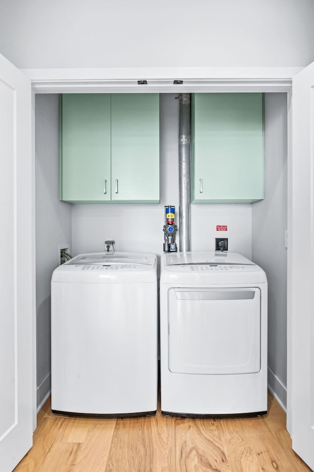 clothes washing area featuring cabinet space, independent washer and dryer, and light wood finished floors
