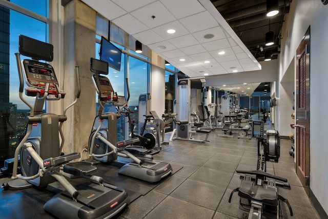 gym with a drop ceiling and a wall of windows