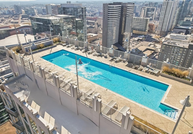 community pool with a city view, fence, and a patio