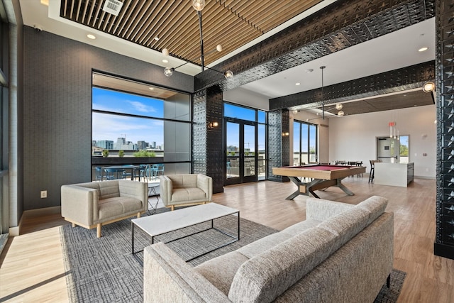 living area featuring pool table, a towering ceiling, wood finished floors, french doors, and a view of skyline