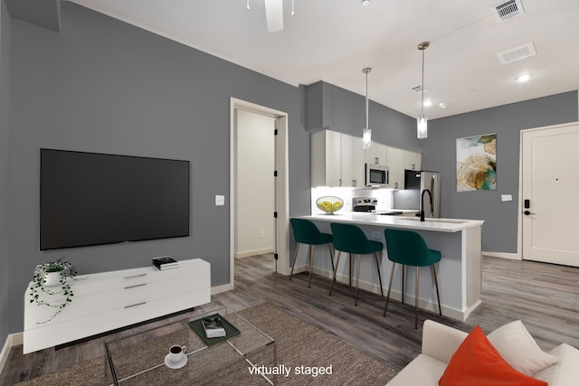 kitchen with appliances with stainless steel finishes, wood finished floors, white cabinetry, baseboards, and recessed lighting