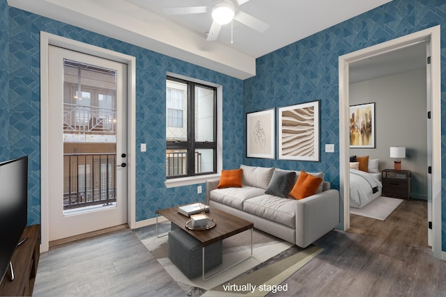 living area featuring wood finished floors, baseboards, a ceiling fan, and wallpapered walls