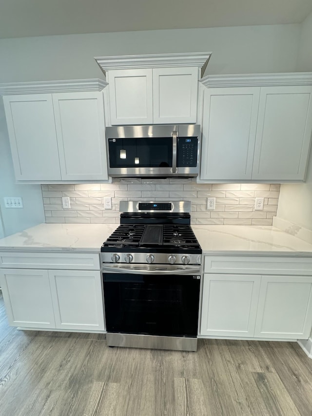 7639 Rookers Bend Dr, Smyrna, TN 37167 - kitchen featuring appliances with stainless steel finishes, light wood-type flooring, white cabinetry, and decorative backsplash