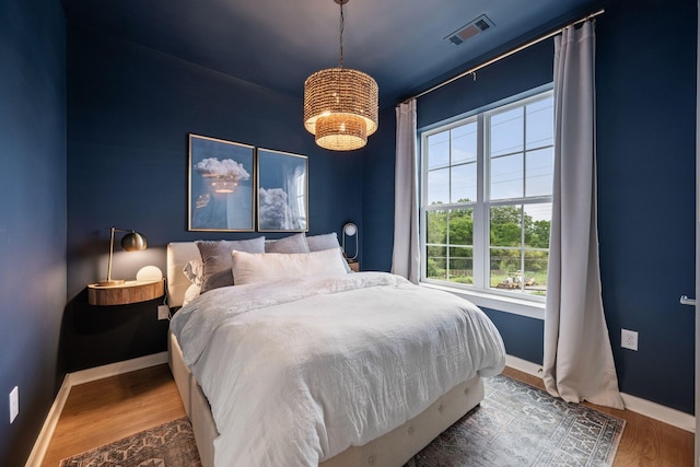 bedroom with baseboards, a chandelier, and wood finished floors