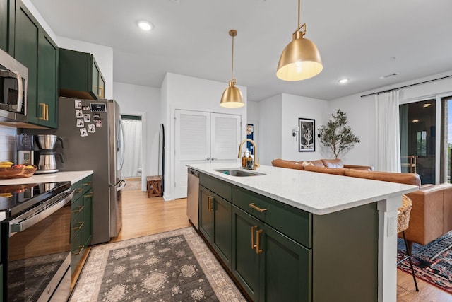 kitchen with green cabinetry, a sink, appliances with stainless steel finishes, light wood-style flooring, and recessed lighting