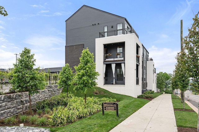 exterior space featuring a balcony and a lawn