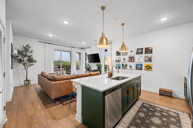 kitchen featuring a sink, stainless steel dishwasher, light wood-type flooring, light countertops, and a kitchen island with sink