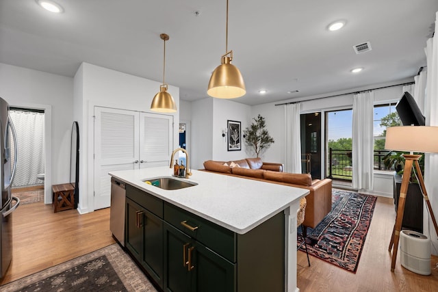 kitchen featuring appliances with stainless steel finishes, a sink, light wood-type flooring, light countertops, and pendant lighting