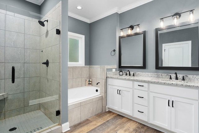 full bathroom with wood finished floors, a stall shower, a bath, crown molding, and double vanity