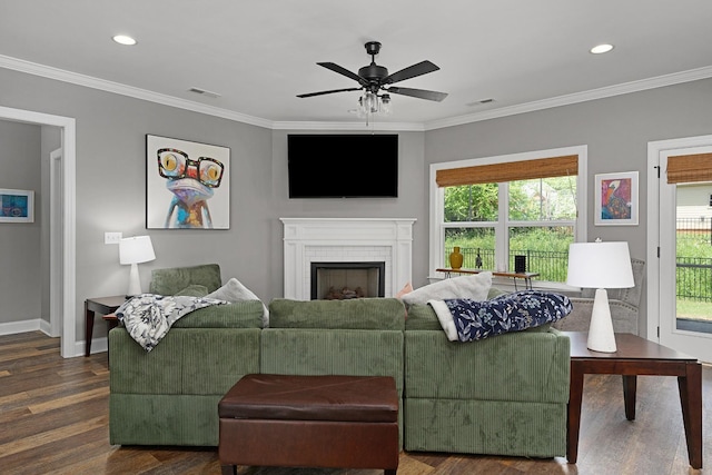 living room with dark wood-style floors, baseboards, crown molding, a brick fireplace, and ceiling fan
