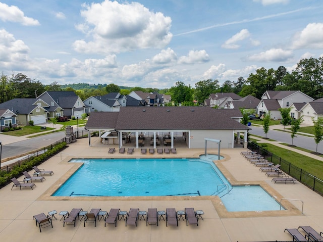 community pool featuring a residential view, fence, and a patio area