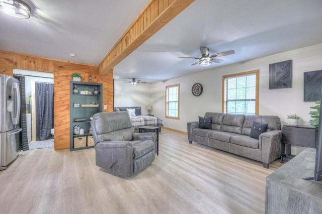 living area featuring light wood finished floors, ceiling fan, baseboards, and wooden walls